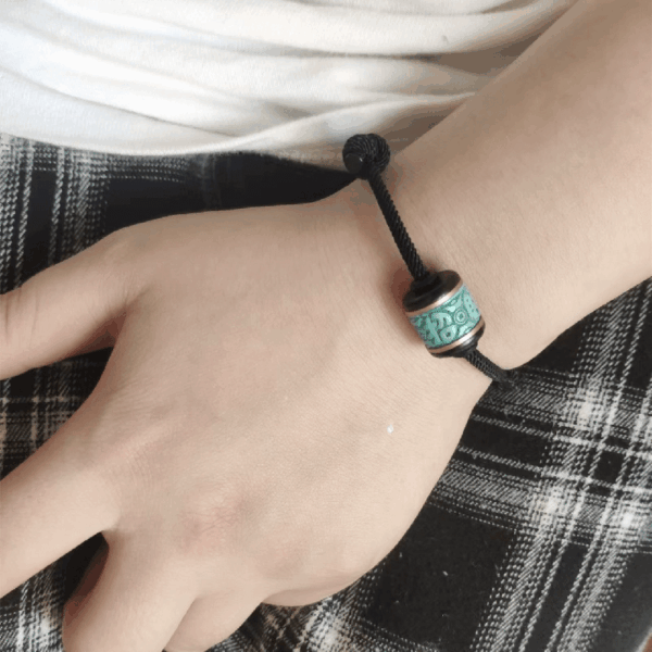 A person wearing the black minimalist cord bracelet on their wrist, showing the fit and scale of the ethnic style jewelry.