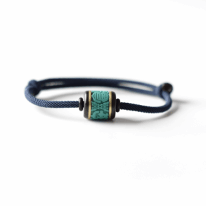 Adjustable Feng Shui bracelet with a turquoise-colored lucky bead on a navy blue cord shown on a white background.