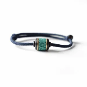 Adjustable Feng Shui bracelet with a turquoise-colored lucky bead on a navy blue cord shown on a white background.